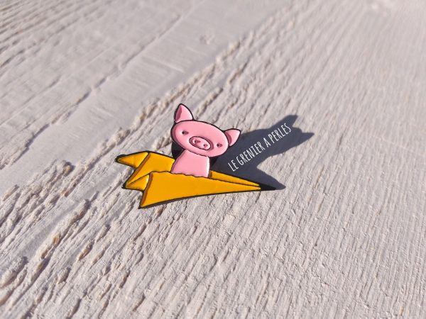 Pin's Petit cochon sur avion en papier